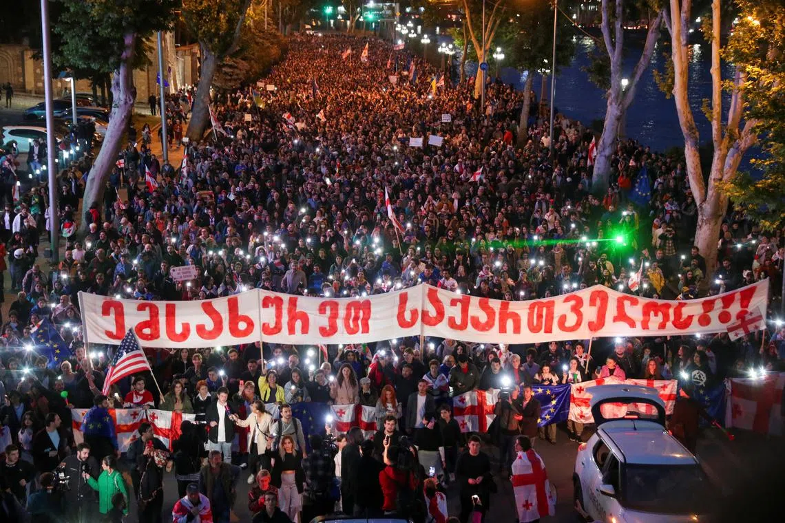 FILE PHOTO: Demonstrators take part in a procession to protest against a bill on \"foreign agents\" and to support Georgia's membership in the European Union, in Tbilisi, Georgia, May 24, 2024. A slogan on the banner addresses Georgian law enforcement officers and reads: \"Serve Georgia\". REUTERS/Irakli Gedenidze/File Photo