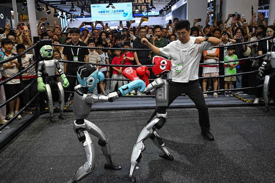 People watching remote-controlled robots by Unitree Robotics boxing during the World Artificial Intelligence Conference (WAIC) at the Shanghai World Expo and Convention Centre in Shanghai on July 28, 2025. 