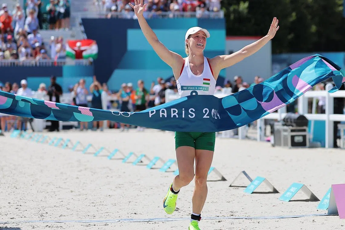Michelle Gulyas of Hungary reacts as she crosses the finish line of the final laser run in the women's modern pentathlon at the Paris Olympics in Versailles on Aug 11, 2024.