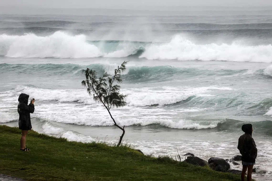 Residents watch massive waves stirred by tropical cyclone Alfred at Byron Bay's Main Beach on March 5, 2025.
