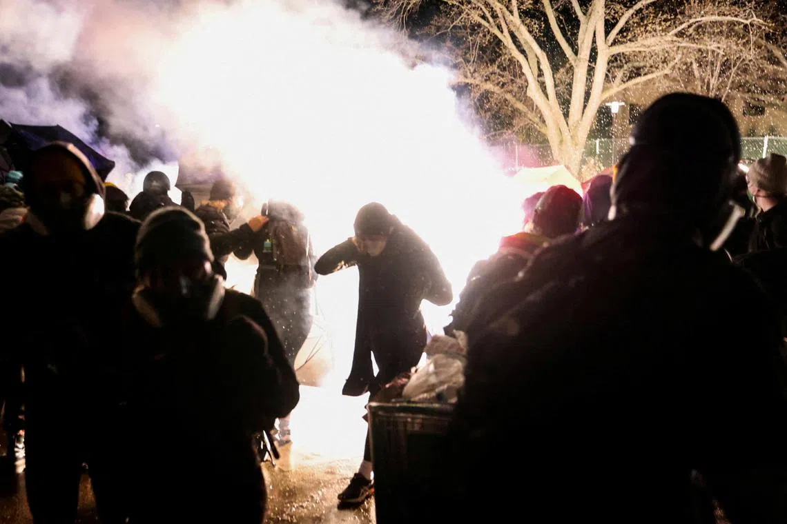 Protesters react amid flash bangs set off by the police.