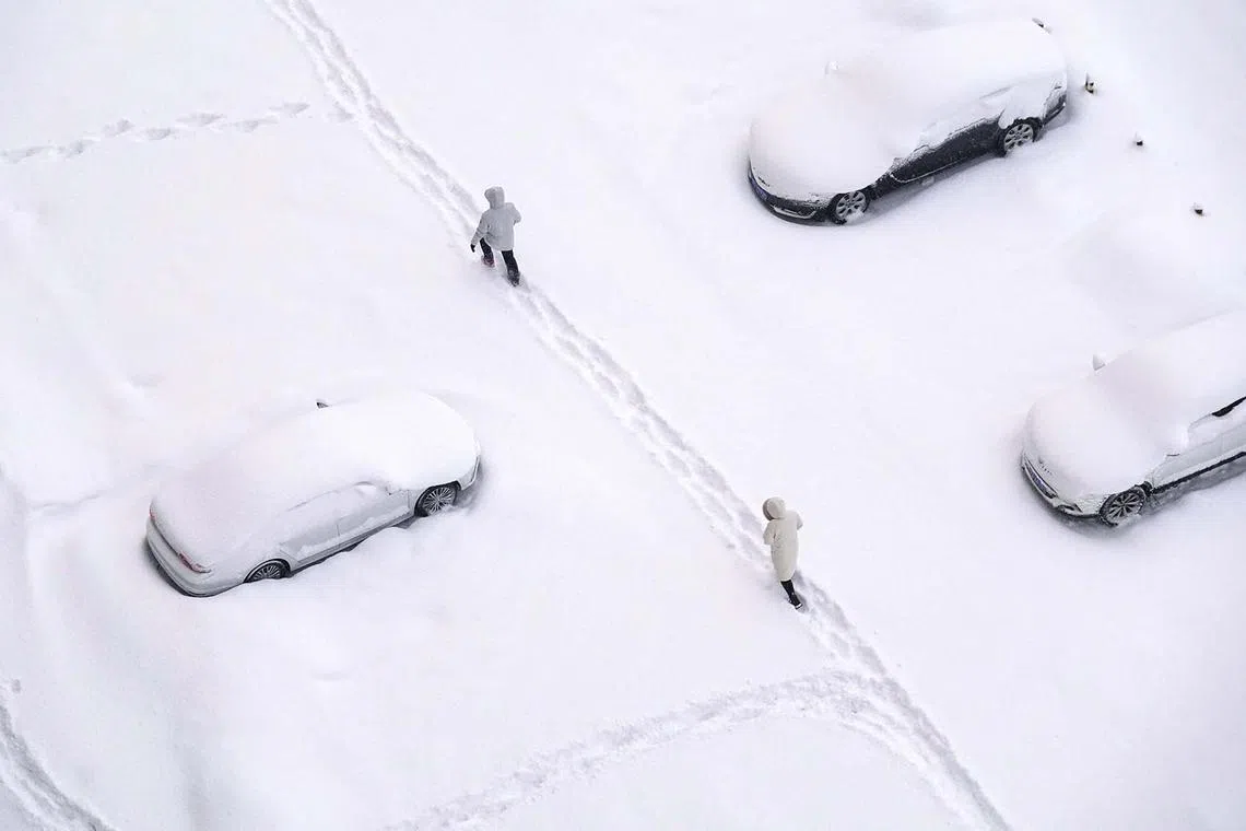 People walking on a snow-covered street during snowfall in Yantai, in China’s eastern Shandong province on Dec 21, 2023. 