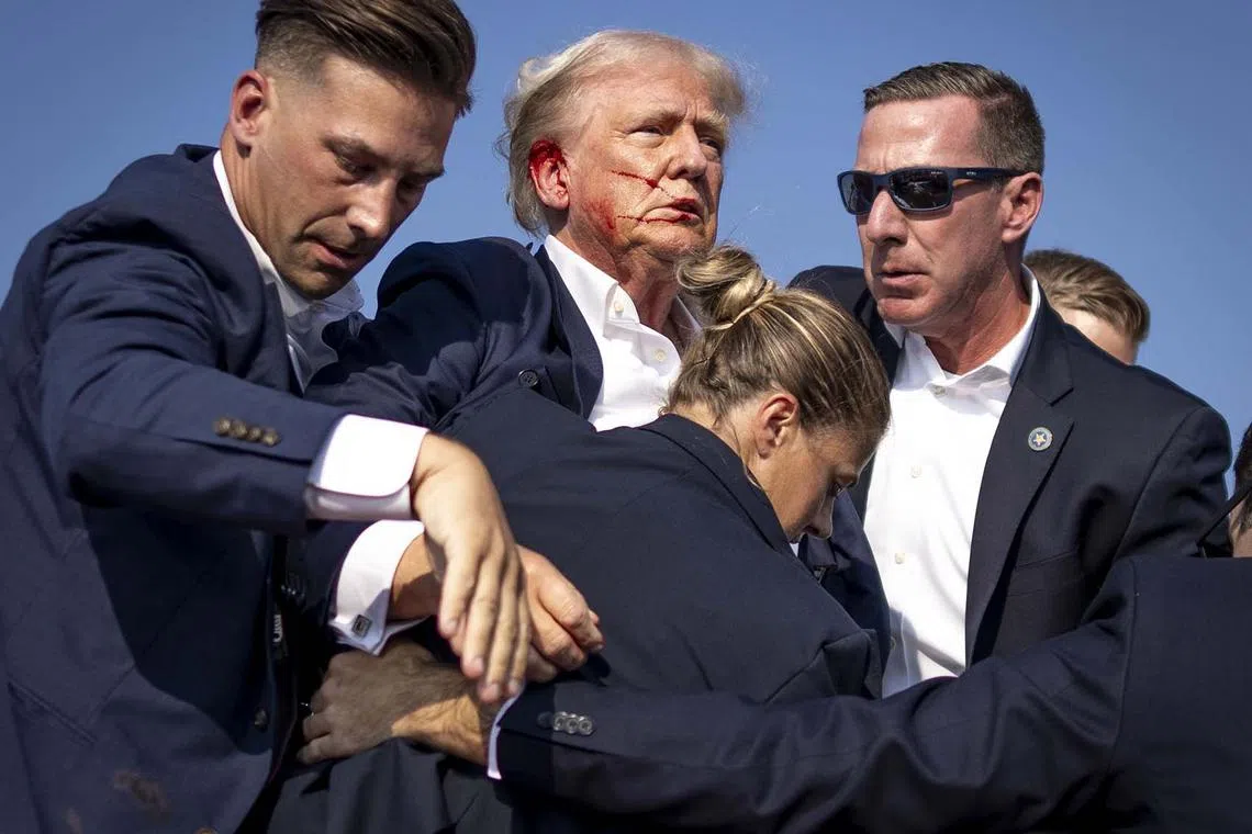 A bloodied Donald Trump is surrounded by Secret Service agents at a campaign rally in Butler, Pennsylvania, on Saturday, July, 13, 2024. The former president was rushed off stage at the rally after shots were fired. 