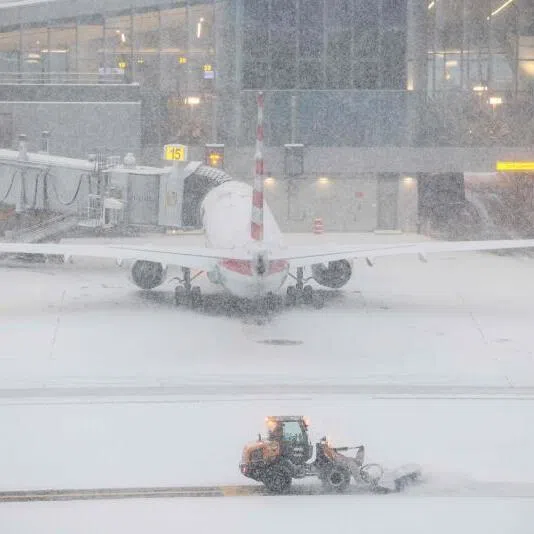 A snow removal machine is seen working on the tarmac of LaGuardia airport in New York on Jan 25, 2026.