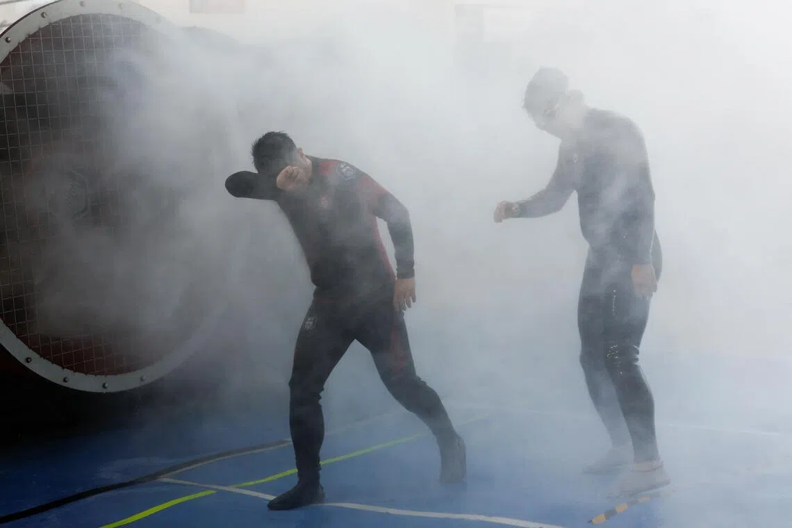 Participants walk through simulated typhoon-force wind and rain during a typhoon survival training session at the Lvxing Disaster Simulation Training Centre.