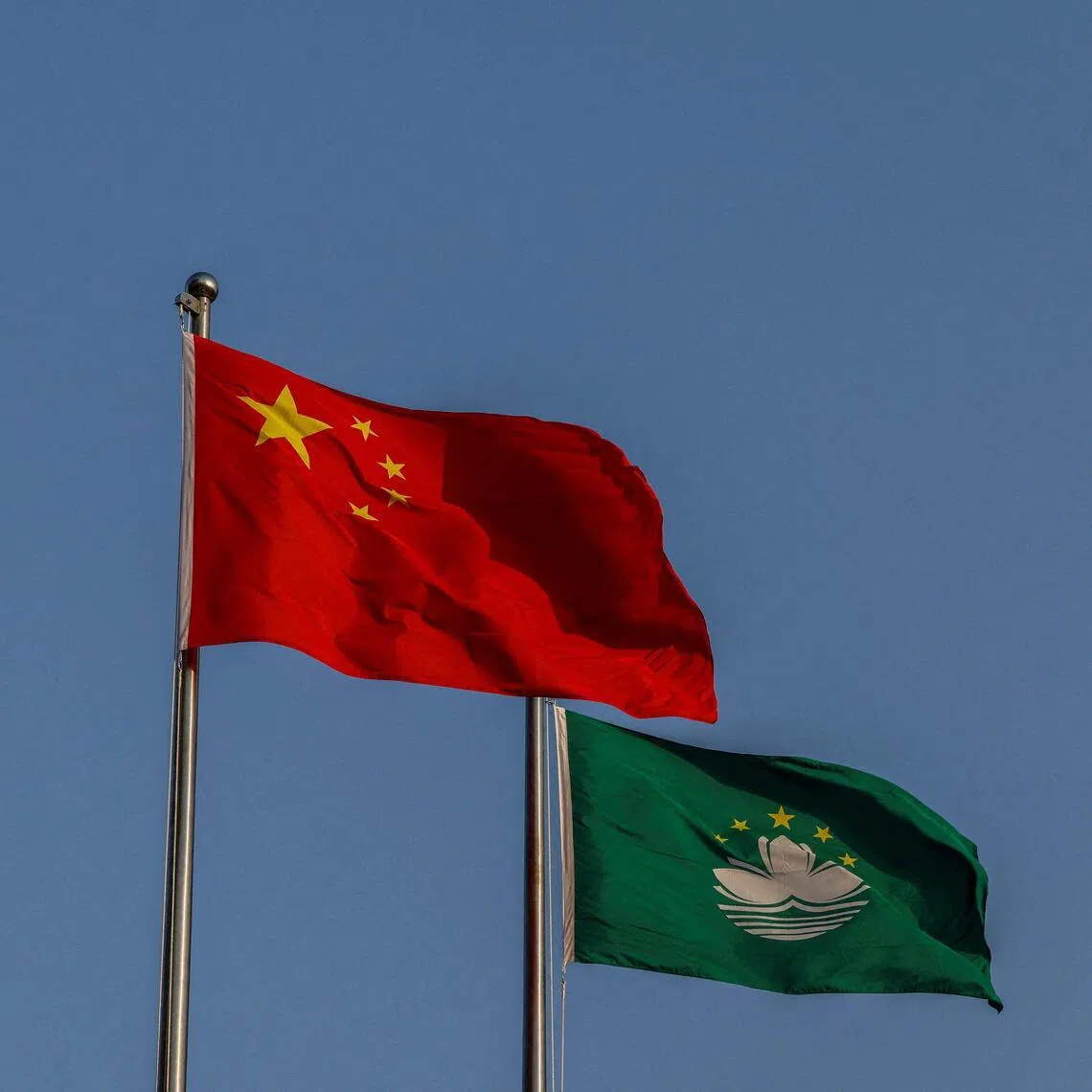 Chinese and Macau flags flutter during a flag-raising ceremony at the Golden Lotus Square to mark the 25th anniversary of Macau's handover from Portugal to China, in Macau on Dec 20, 2024. 
