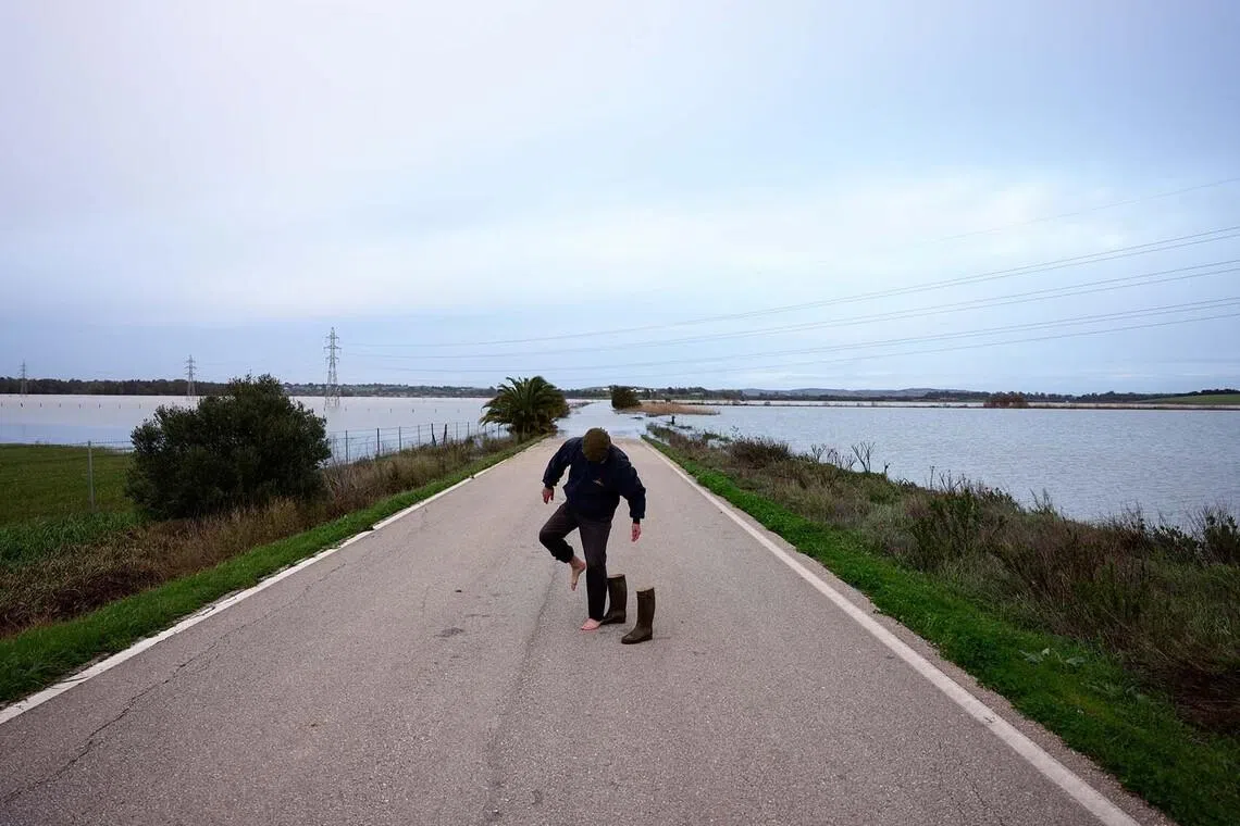 Vicente Diosdado, 54, industrial engineer, removing his boots as he waits on a flooded road after having asked authorities for help to access his isolated family farm in order to feed their ten thoroughbred horses and some dogs, which have gone for two days without being fed due to the overflowing of Guadalete River after heavy rains, as Storm Marta hits parts of Spain, in Jerez de la Frontera, Spain, Feb 8, 2026. 