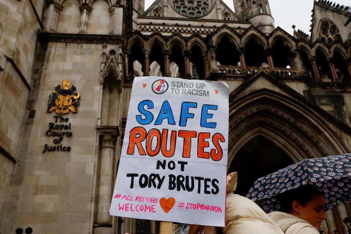 FILE PHOTO: A protestor holds a placard while demonstrating outside the High Court over the legal challenge against the government's policy to deport illegal immigrants to Rwanda in London, Britain December 19, 2022. REUTERS/Peter Nicholls/File Photo