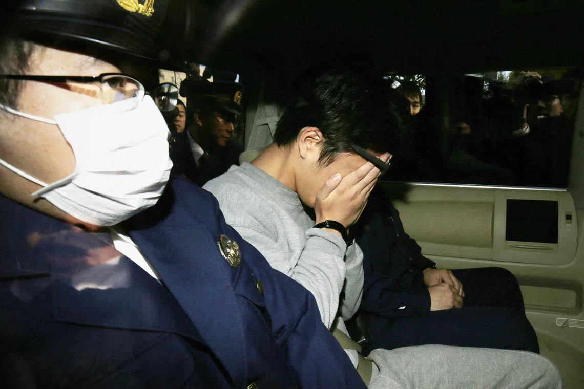 Suspect Takahiro Shiraishi (C) covers his face with his hands as he is transported to the prosecutor's office from a police station in Tokyo on November 1, 2017. The 27-year-old Japanese man, who was arrested after police found nine dismembered corpses rotting in his house, has confessed to killing all his victims over a two-month spree after contacting them via Twitter, media reports. (Photo by JIJI PRESS / AFP) / Japan OUT