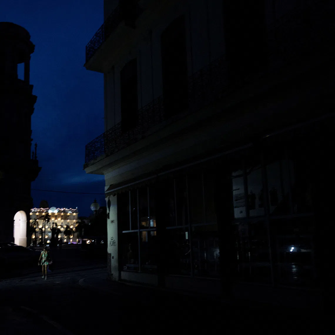 People walk along a darkened street during a power outage as a hotel remains illuminated in the background in Havana, Cuba, September 16, 2026. REUTERS/Ricardo Arduengo