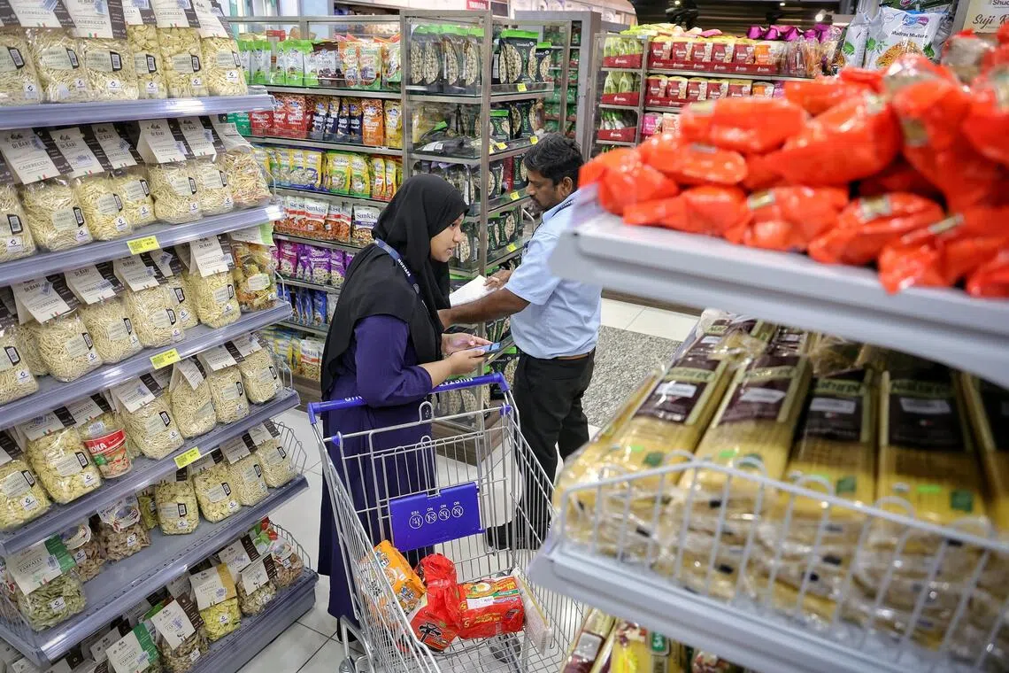 The picker and packer team of Zafira (left) and Pandi Karthik looking down different aisles for items to fulfill an online order at Mustafa Centre on Oct 31, 2025.