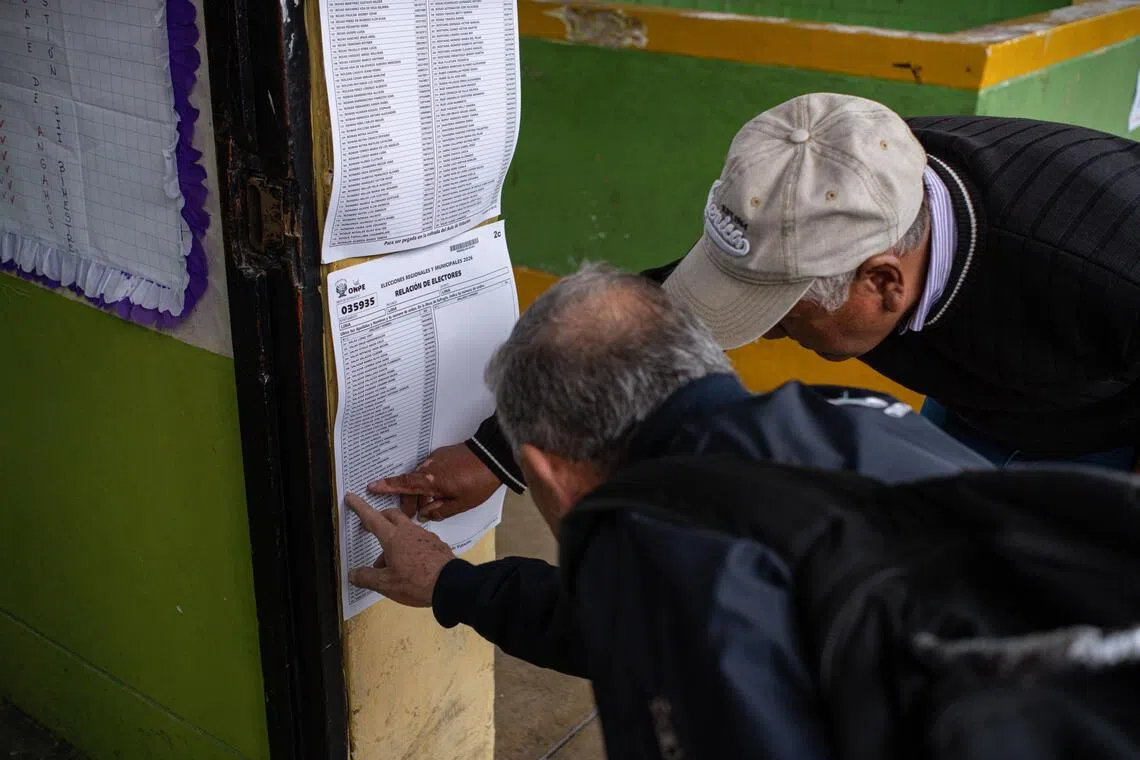 epa13280980 Two men are looking for their polling station on a list for the regional and municipal elections in Lima, Peru, 04 October 2026. More than 26.3 million voters are called to the polls to elect a total of 13,148 regional and municipal authorities.  EPA/Paolo Aguilar