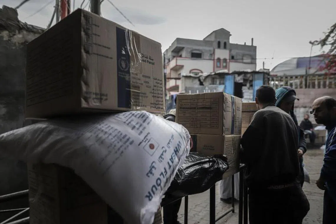 Palestinians collect food aid packages from a United Nations Relief and Works Agency (UNRWA) warehouse in Deir Al-balah, Gaza, on Thursday, Jan. 23, 2025. UNRWA, with well-established warehouses, vehicles, and manpower, has actively led the distribution of aid to more than 90% of Gaza’s population who have been displaced by war into southern Gaza. Photographer: Ahmad Salem/Bloomberg