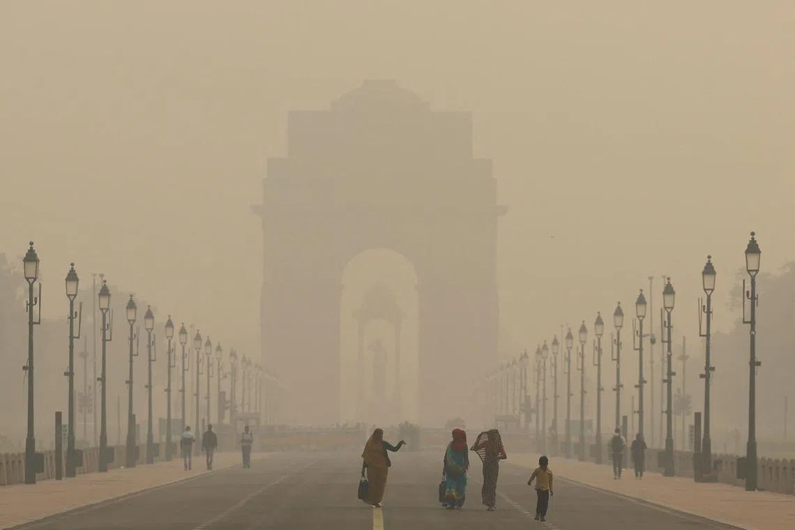 Women walking on a road near India Gate as the sky is enveloped with smog after Delhi's air quality worsened due to air pollution on Nov 19.    