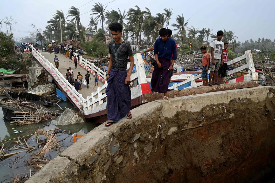 People crossing a broken bridge at the Khaung Dote Khar Rohingya refugee camp in Sittwe, on May 15, after cyclone Mocha made a landfall. 