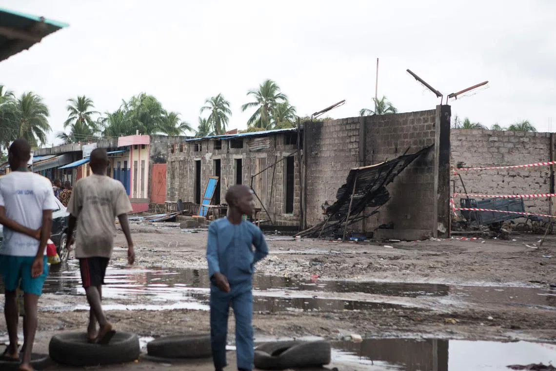 People walk past the burned out remains of a contraband fuel depot near the Benin-Nigeria border.