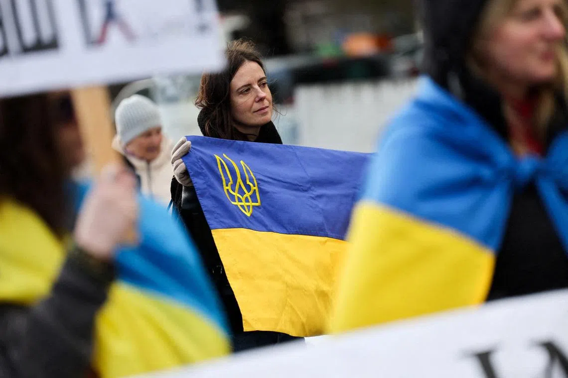 A woman holds a Ukrainian flag at a protest near the United Nations office, on the day of U.S.-mediated peace talks between Russia and Ukraine in Geneva, Switzerland, February 17, 2026. REUTERS/Pierre Albouy