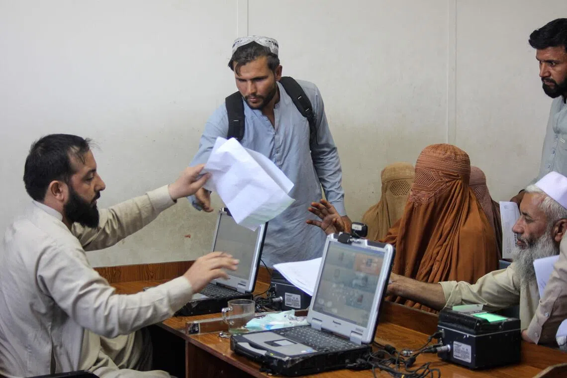 An official worker (left) registering paperwork for Afghan returnees deported from Pakistan, at Omari camp near the Afghanistan-Pakistan border crossing in Torkham.