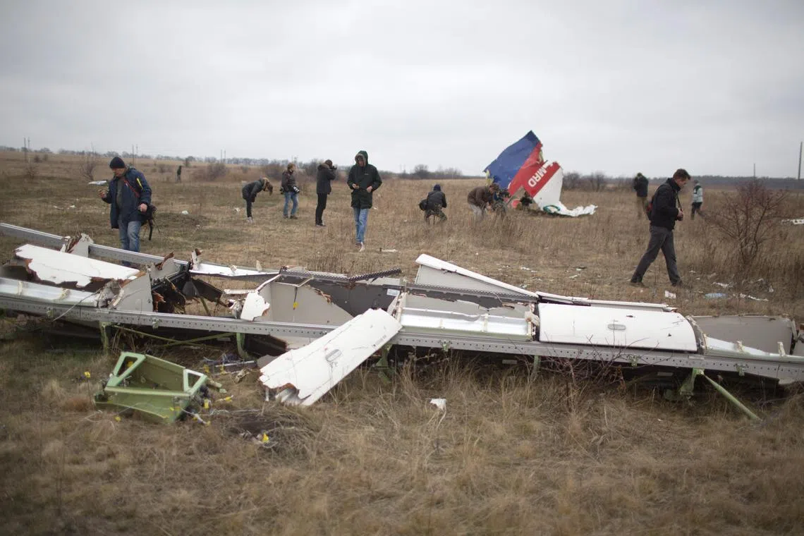 In a file photo taken on Nov 11, 2014, journalists look at parts of Malaysia Airlines MH17 at the crash site in Donetsk, Ukraine.