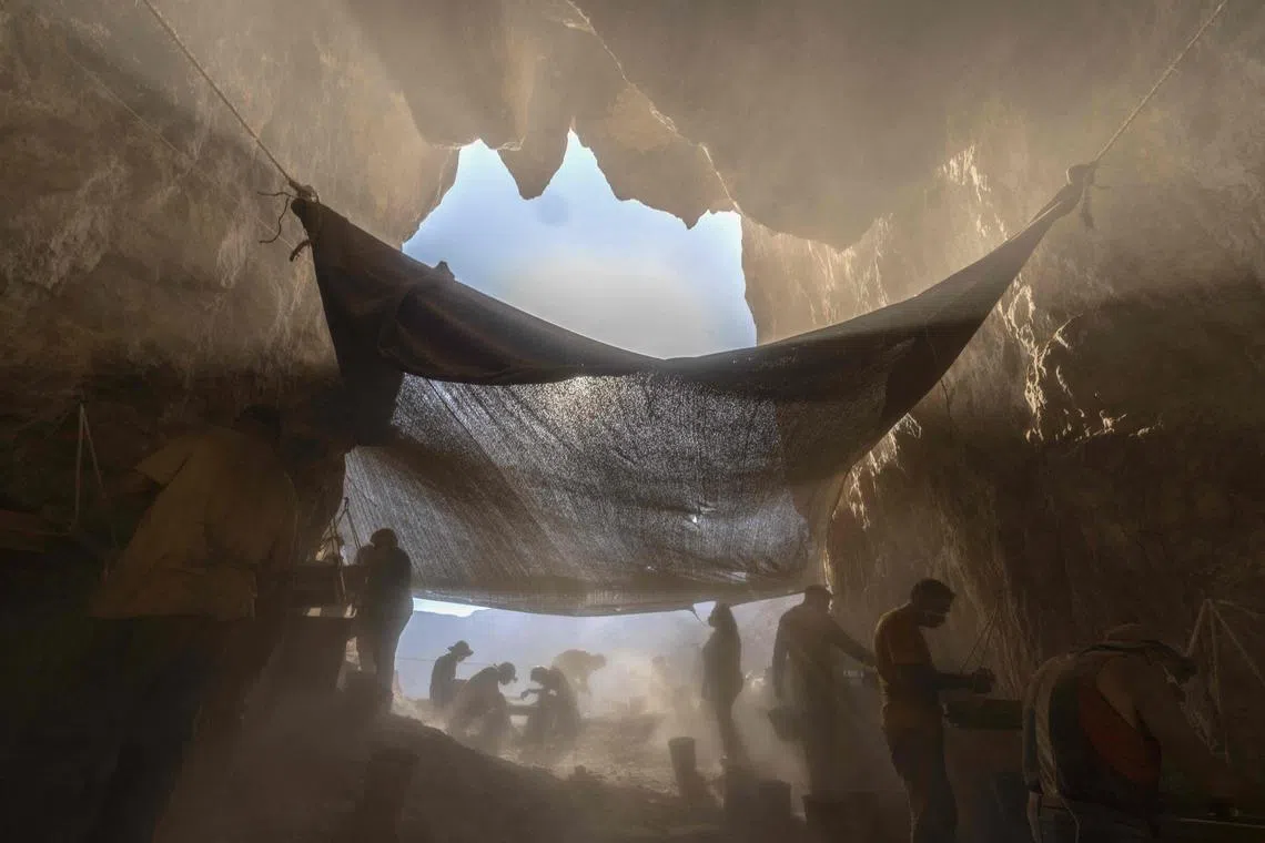 Members of the Israel Antiquities Authority (IAA) team sift soil at an excavation site in the Murabaat cave in the Judean Desert area near the Dead Sea, on December 28, 2022. The IAA's expedition aims to find more of the known Dead Sea scrolls and other finds from some 2000 years ago at the cave, which was discovered in 1951 and was subsequently excavated and partially surveyed. 