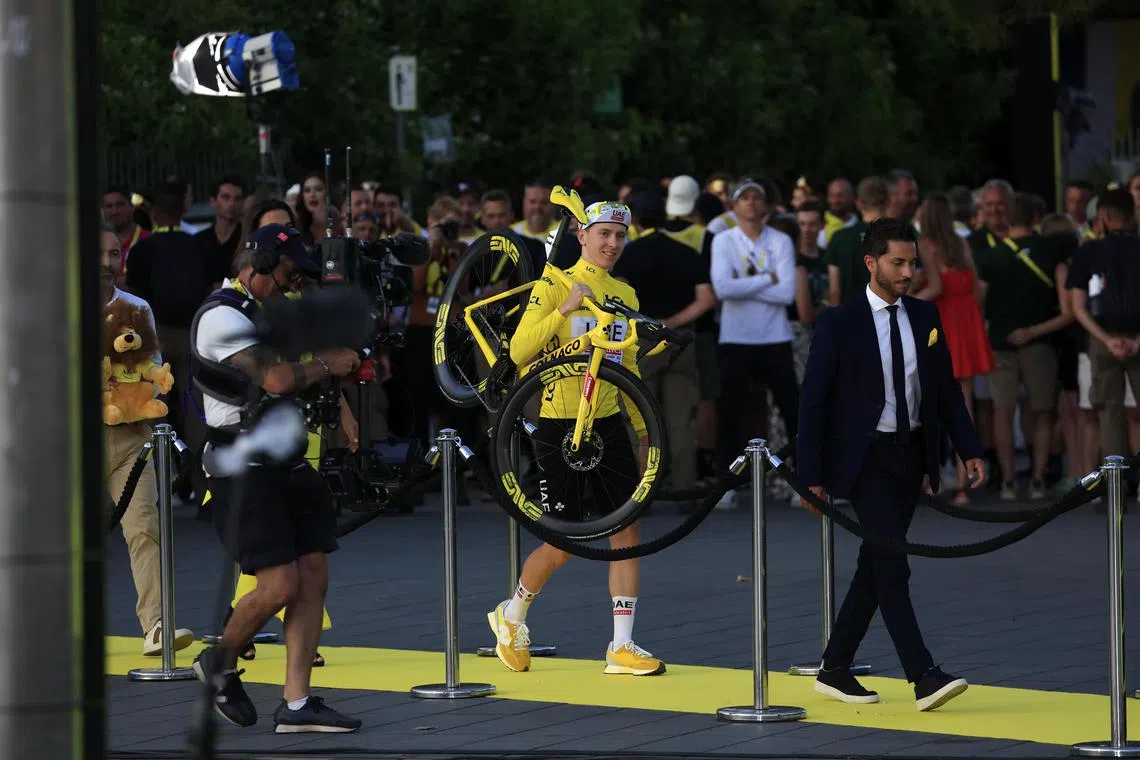 Yellow jersey and Tour de France winner Tadej Pogacar of UAE Team Emirates carries his bike onto the podium on July 21.