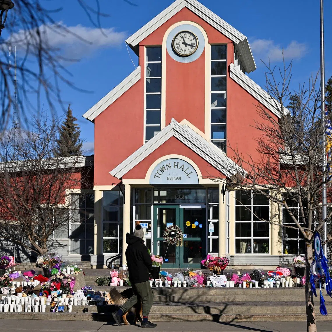 A person visits a growing makeshift memorial on the steps of the town hall, four days after one of the worst mass shootings in recent Canadian history, in the town of Tumbler Ridge, British Columbia, Canada February 14, 2026. REUTERS/Jennifer Gauthier