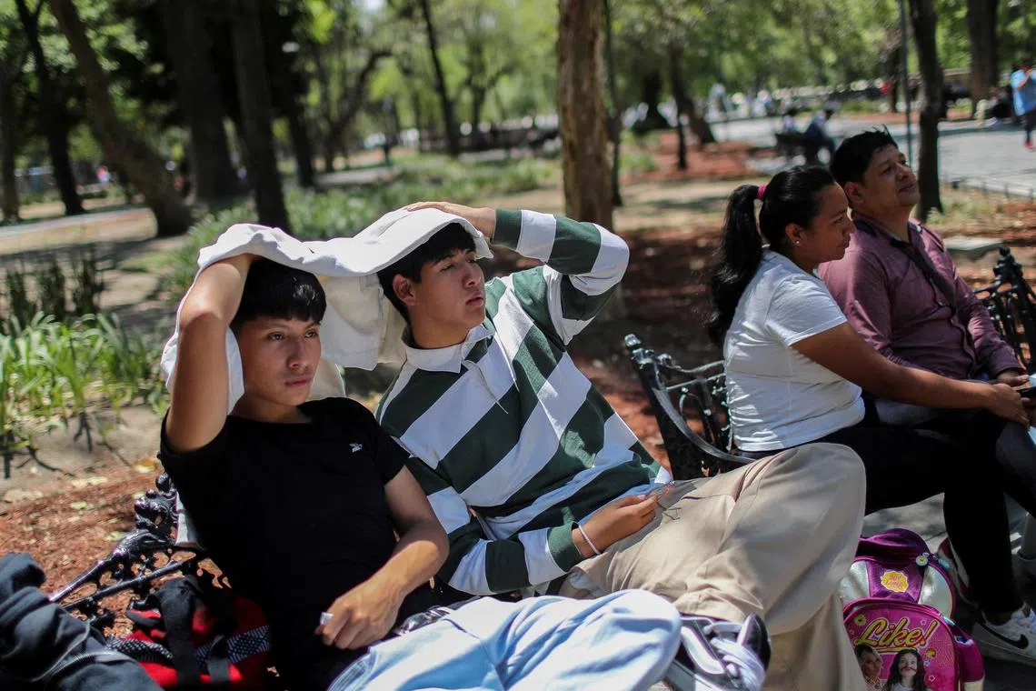 FILE PHOTO: Men use a sweatshirt to protect themselves from the sun during a heat wave in Mexico City, Mexico April 16, 2024. REUTERS/Raquel Cunha/File Photo