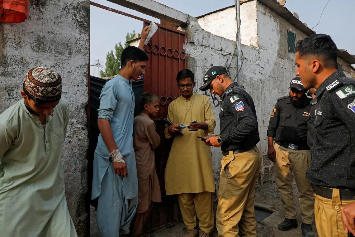 FILE PHOTO: Police officers, along with workers from the National Database and Registration Authority (NADRA), check the identity cards of Afghan citizens during a door-to-door search and verification drive for undocumented Afghan nationals, in an Afghan Camp on the outskirts of Karachi, Pakistan, November 21, 2023. REUTERS/Akhtar Soomro/File Photo