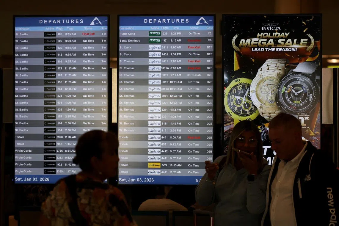 Passengers stand next to screens displaying flight information at Luis Munoz Marin International Airport in Carolina, Puerto Rico, on Jan 3.