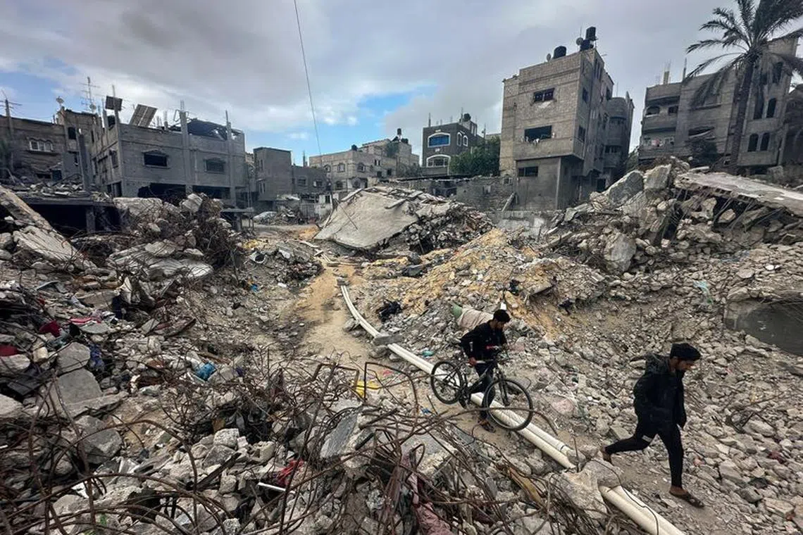 Palestinians walk among the rubble, as they inspect houses destroyed in Israeli strikes during the conflict, amid the temporary truce between Hamas and Israel, at Khan Younis refugee camp in the southern Gaza Strip November 27, 2023. REUTERS/Mohammed Salem