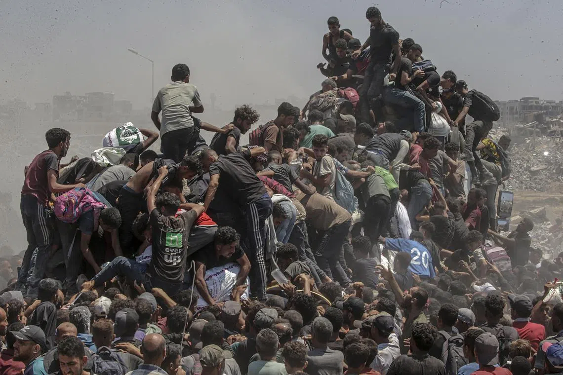 A throng of desperate men and boys overwhelm a truck carrying food aid at a distribution point in northern Gaza on July 27, 2025.