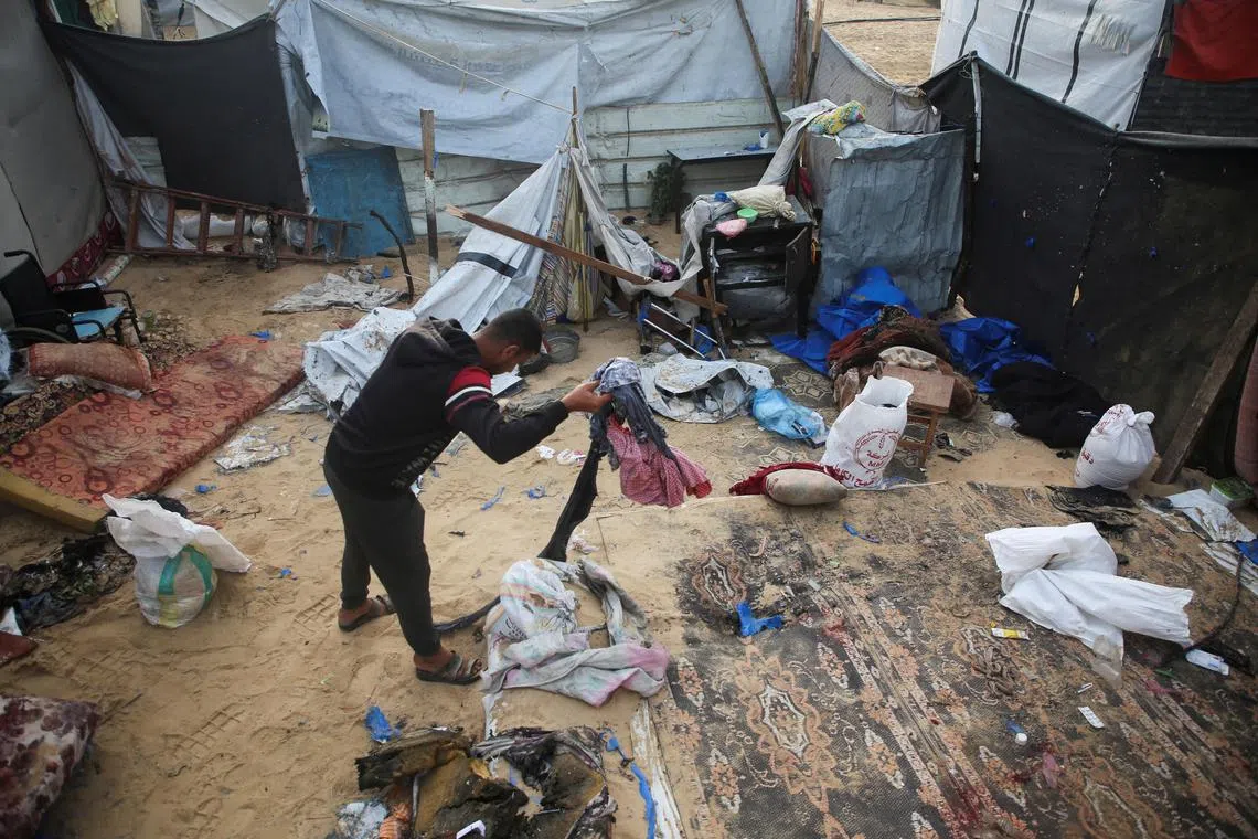A Palestinian inspects the site of an Israeli strike on a tent housing displaced people, in Khan Younis.