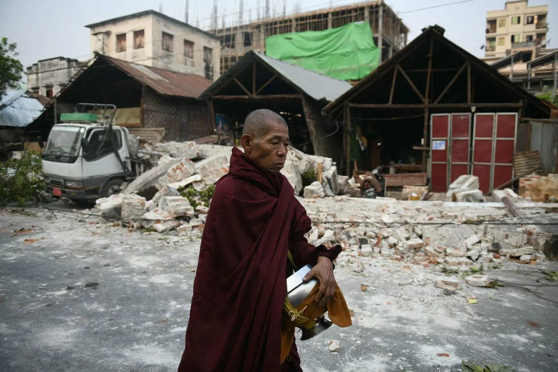 TOPSHOT - A monk walks past damaged houses in Mandalay on March 30, 2025, two days after an earthquake struck central Myanmar. The death toll from a huge earthquake that hit Myanmar and Thailand passed 1,600, as rescuers dig through the rubble of collapsed buildings in a desperate search for survivors. The quake destroyed buildings, downed bridges and buckled roads across swathes of Myanmar, with massive destruction seen in Mandalay. (Photo by Sai Aung MAIN / AFP)