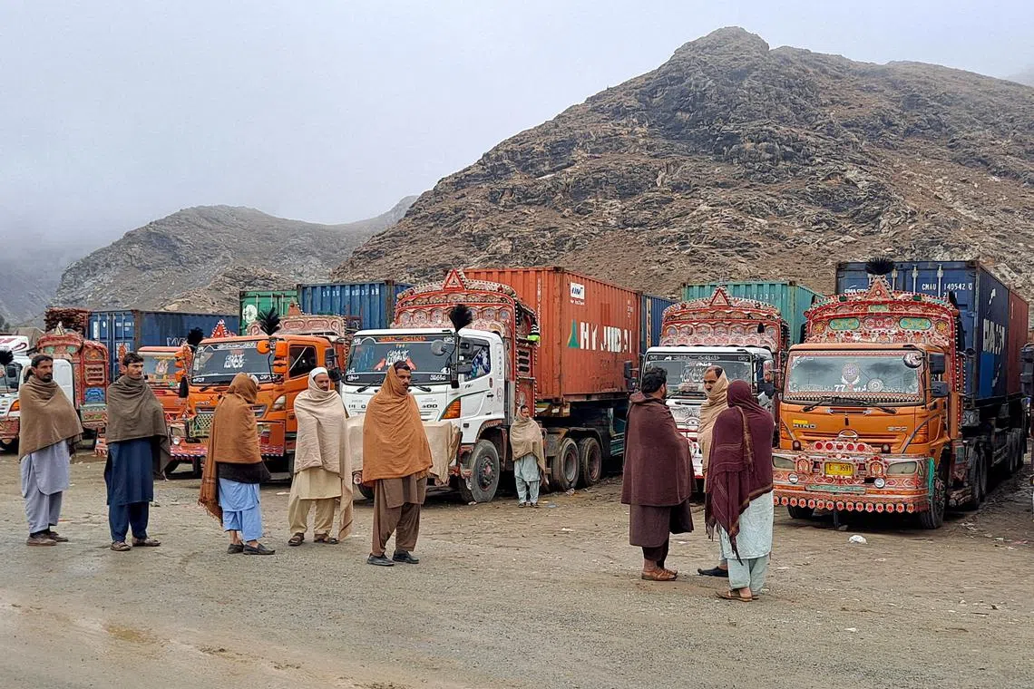 FILE PHOTO: People stand next to parked trucks loaded with supplies at the Torkham border crossing following the closure of the border crossing between Pakistan and Afghanistan, March 3, 2025. REUTERS/Shahid Shinwari/File Photo