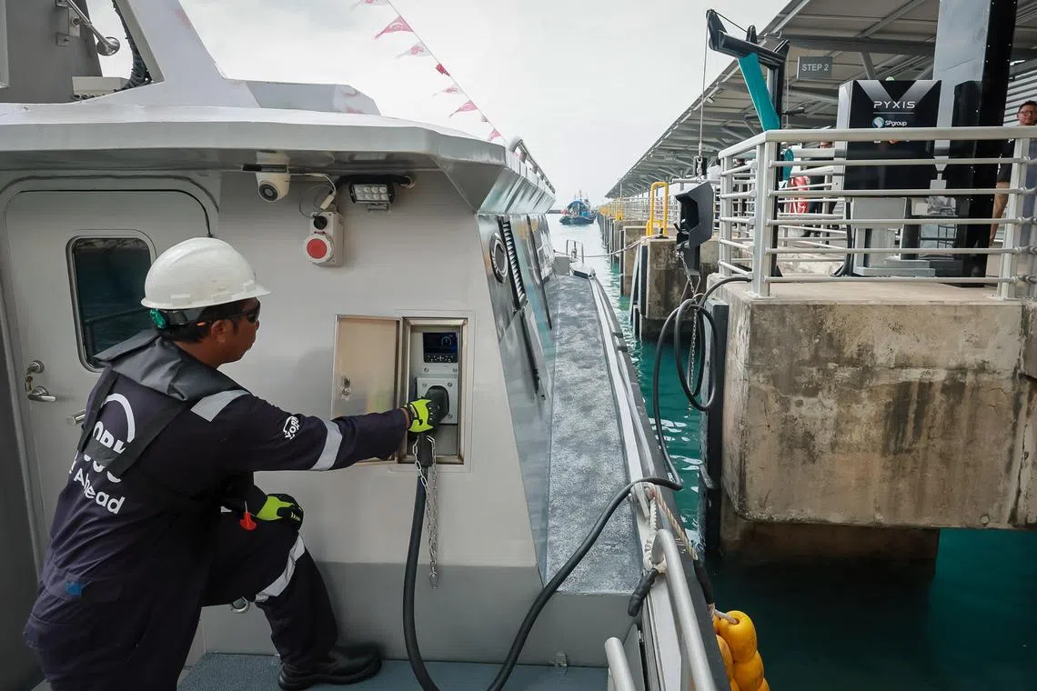A worker plugging an electric cable into the charging port of Pyxis X Tron, a fully-electric passenger vessel, berthed at Marina South Pier, April 8, 2024.