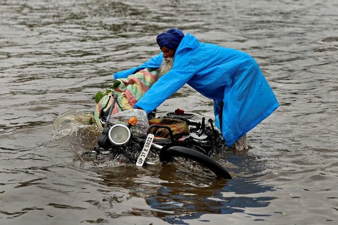 A man tries to hold on to his motorbike as it falls in a flooded road during heavy rains in New Delhi, India, July 9, 2026. REUTERS/Anushree Fadnavis TPX IMAGES OF THE DAY