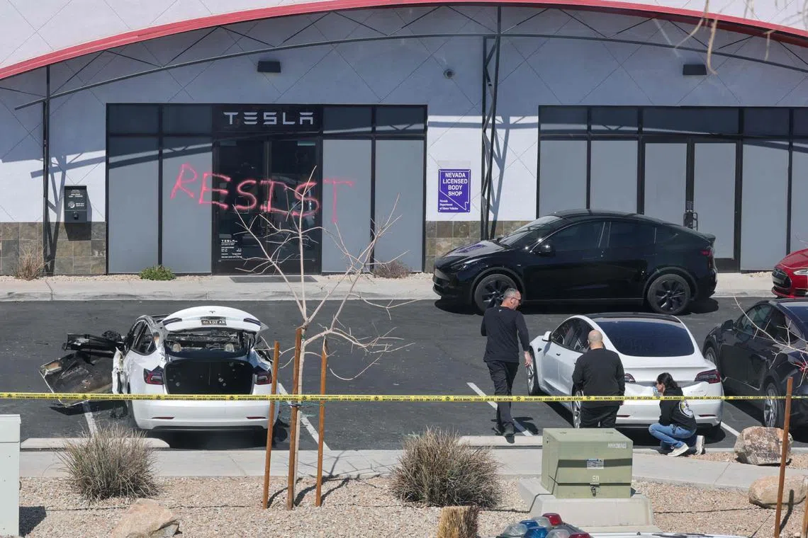 Investigators look over the scene at a Tesla Collision Center after an individual set vehicles on fire in Las Vegas on March 18.