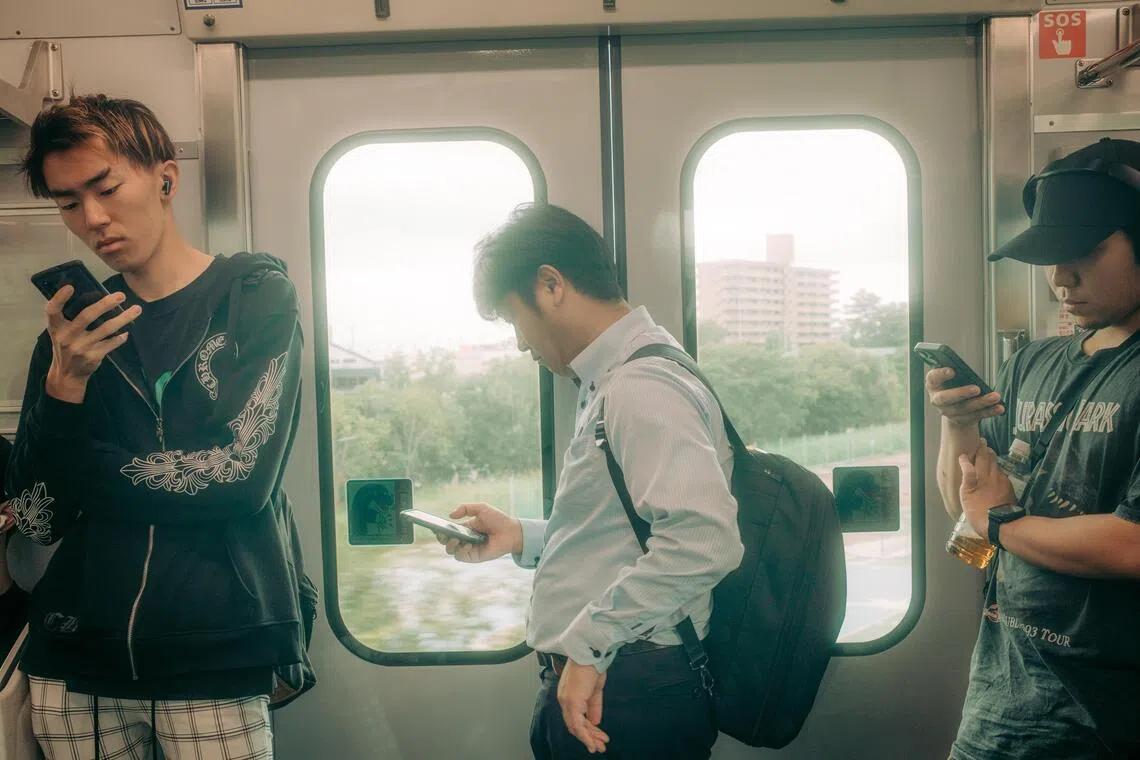 Smartphones help passengers pass the time on a train near Toyoake, Japan, on Sept. 29, 2025. Authorities in Toyoake introduced a rule limiting the use of digital devices to two hours per day outside of work and school. (Kentaro Takahashi/The New York Times)