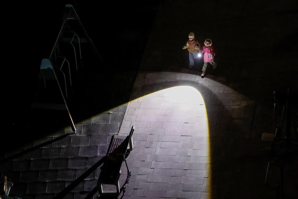 Children in Ukraine use a flashlight amid a power blackout after critical civil infrastructure was hit by Russian missile and drone attacks.