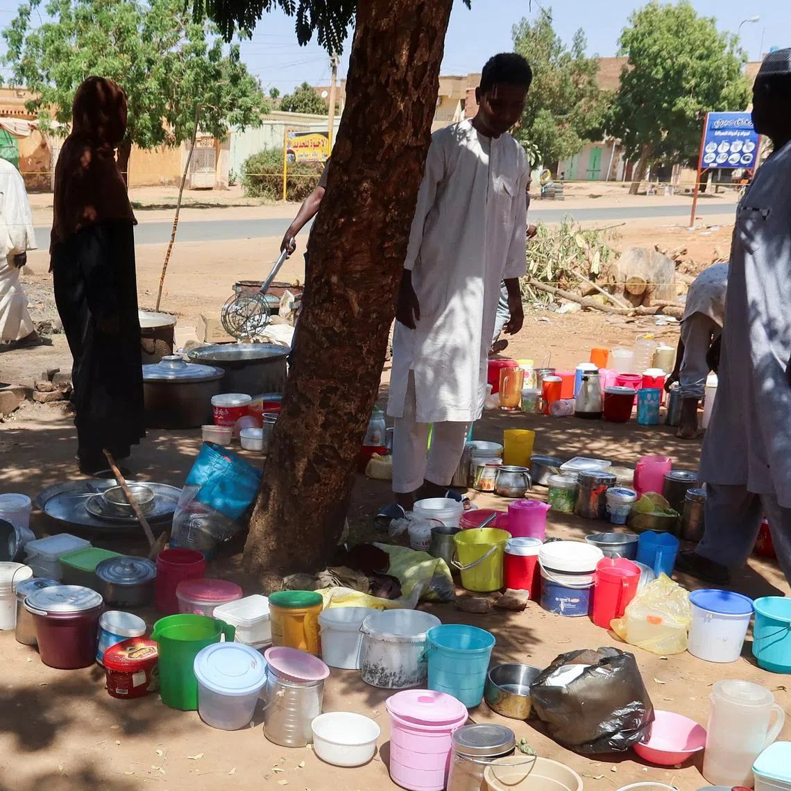 FILE PHOTO: Sudanese men stand next to empty containers in front of \"Takaya\" the charity restaurant and a community kitchen, that helps the needy Sudanese in Omdurman areas recently controlled by army during the conflict and war, during the holy month of Ramadan in the state of Khartoum, Sudan March 14, 2025. REUTERS/El Tayeb Siddig/File Photo
