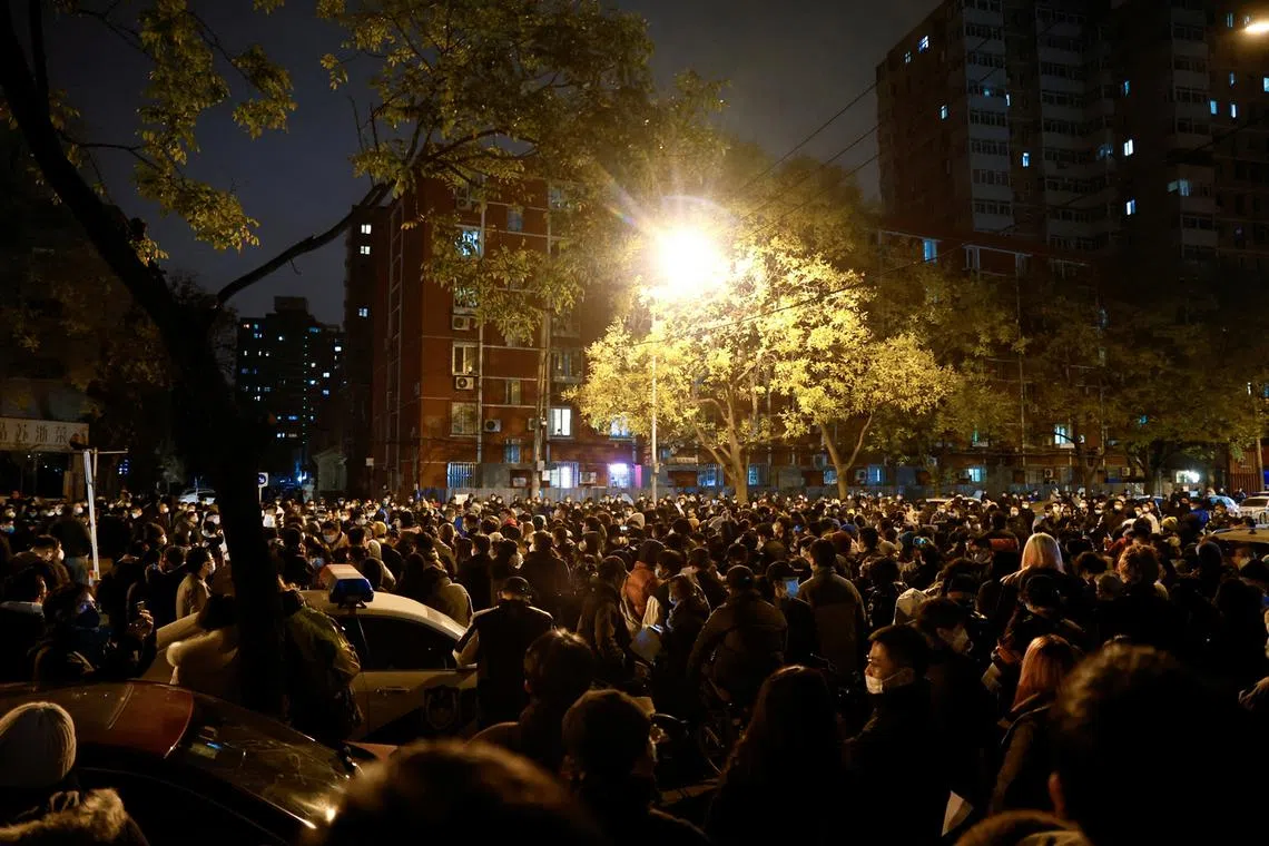 People gather for a vigil and hold white sheets of paper in protest of coronavirus disease restrictions, as they commemorate the victims of a fire in Urumqi, as outbreaks of the coronavirus disease continue in Beijing, China, Nov 27, 2022. 