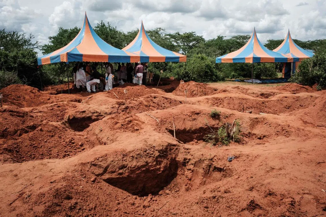 Workers take shelter while digging the ground to exhume bodies from a mass-grave site in Shakahola, Kenya.