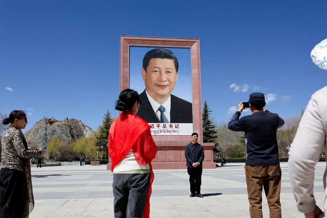 FILE PHOTO: People take photo in front of a large portrait of Chinese President Xi Jinping, during a government-organized tour, at Potala Palace Square in Lhasa, Tibet Autonomous Region, China, March 28,  2025. REUTERS/Go Nakamura//File Photo