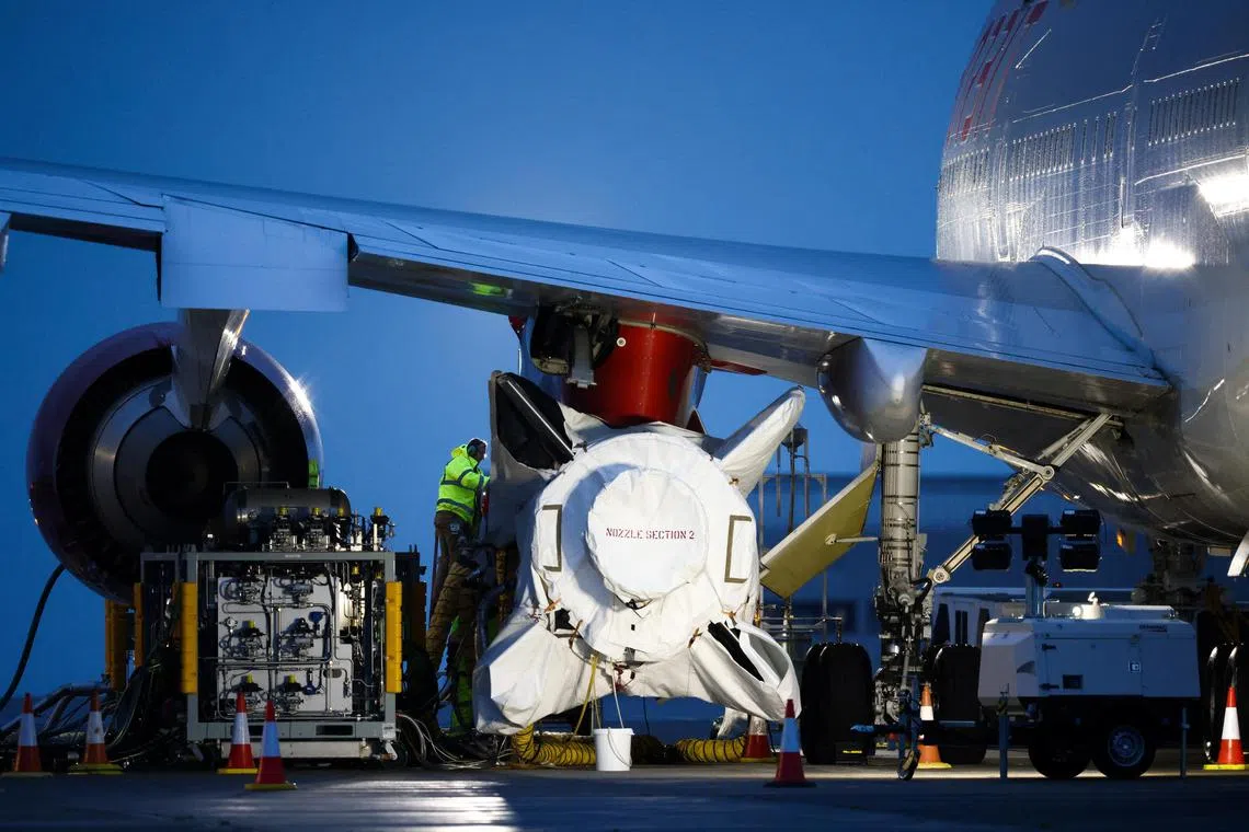 Technicians work on Virgin Orbit's LauncherOne rocket, attached to the wing of Cosmic Girl, a Boeing 747-400 aircraft, at Spaceport Cornwall at Newquay Airport, on Jan 8, 2023. 