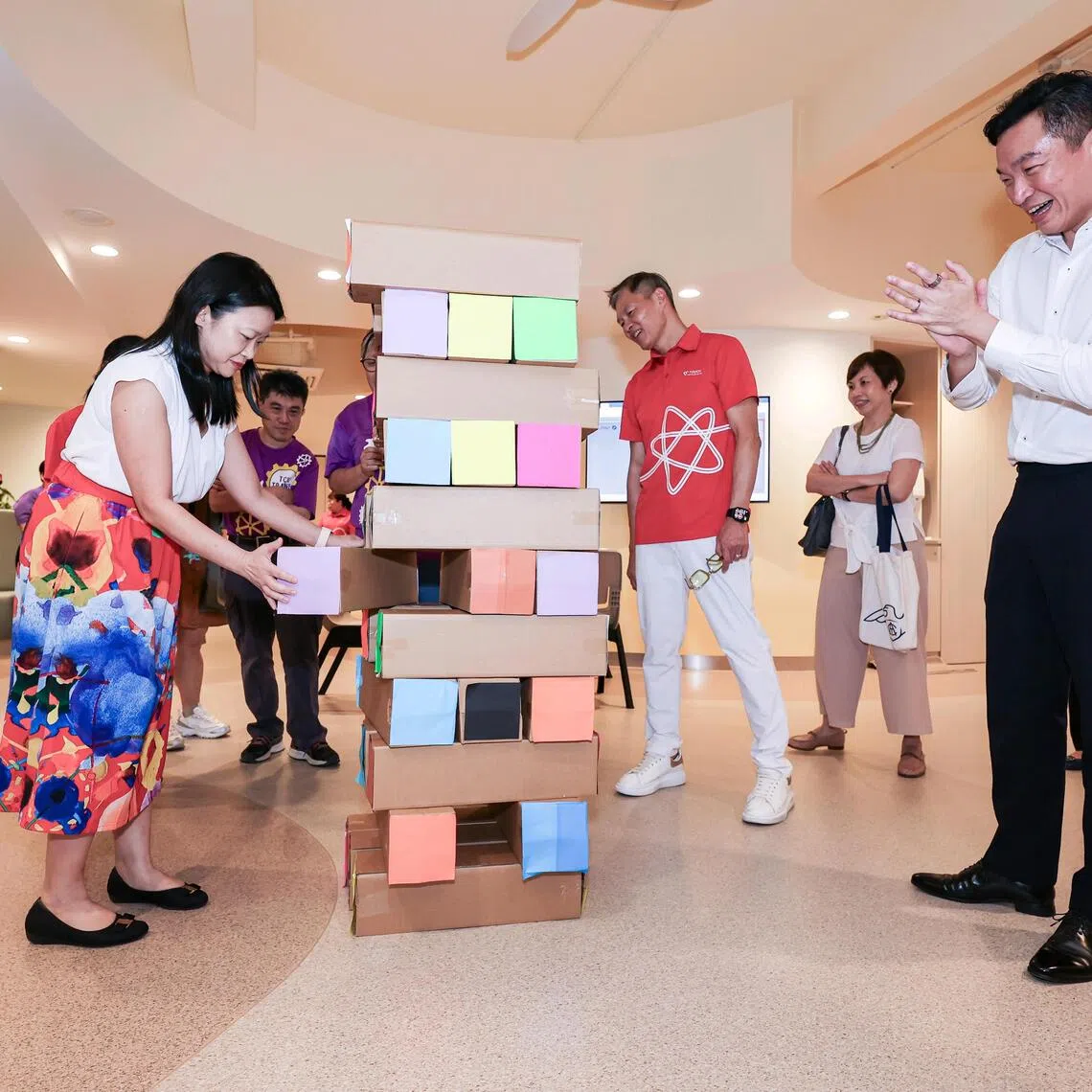 (From left) SG Enable CEO Lee May Gee removing a Jenga block as Senior Parliamentary Secretary for Law and Social and Family Development Eric Chua and Touch Community Services CEO James Tan cheer on at the opening of the TOUCH Centre for Independent Living at Enabling Village on July 31.