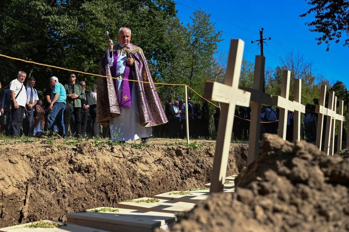 A priest conducts a mass burial ceremony of Poles killed by Ukrainian nationalists during World War II, in the former Polish village of Puznyky, in Ternopil region, Ukraine September 6, 2025. Last year Ukraine granted Poland access to the sites in the West part of the country, once part of Poland, to carry out joint search and exhumation of the remains of Polish victims. REUTERS/Anastasiia Smolienko