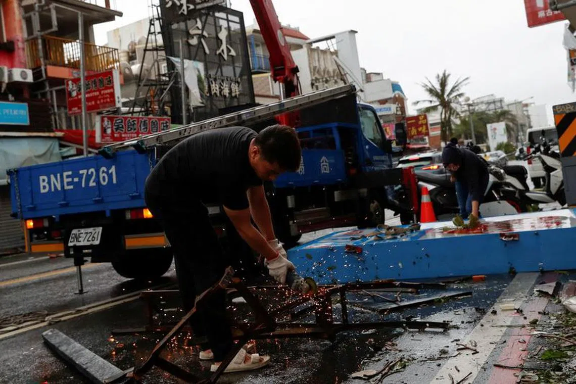 FILE PHOTO: A worker cuts the metal structure of a fallen sign before carrying it to truck after Typhoon Koinu passed the southern tip of Taiwan, in Kenting, Taiwan October 5, 2023. REUTERS/Carlos Garcia Rawlins/File Photo