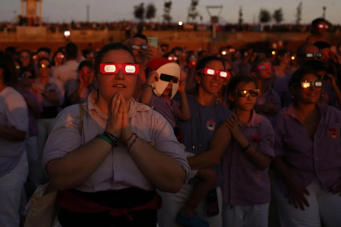 People react as they observe the total solar eclipse from the sea port of Tarragona, northeastern Spain, on August 12, 2026. Millions of Europeans contemplated the sky in awe today during a rare total solar eclipse that will plunge a swathe of Spain into an eerie daytime darkness. The shadow cast when the Moon covers the Sun began in Russia's remote Arctic north at around 1700 GMT and continued in an arc through Greenland and Iceland. Spain is where most people viewed the total eclipse, which crossed the country diagonally from the northern Atlantic coast to the Mediterranean Sea, where it vanished at around 1830 GMT. (Photo by Josep LAGO / AFP)