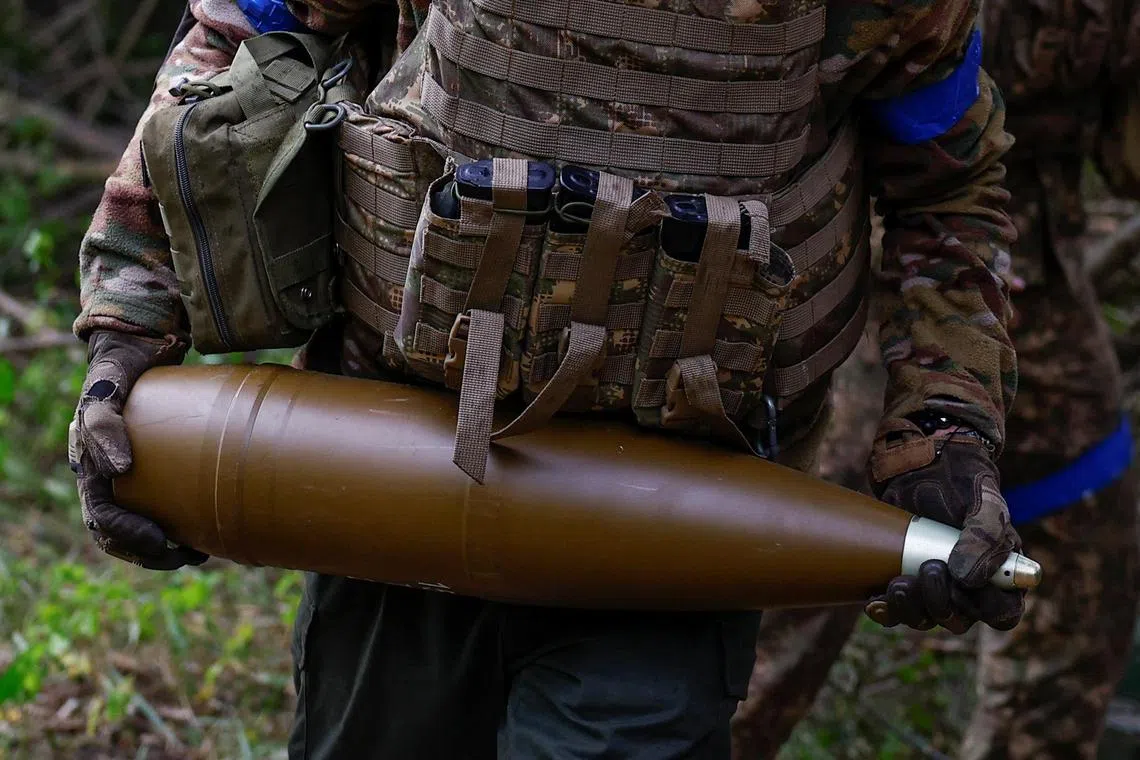 A Ukrainian serviceman carries a 152mm shell for loading into a D-20 howitzer, on the front line in Ukraine's Kharkiv region.