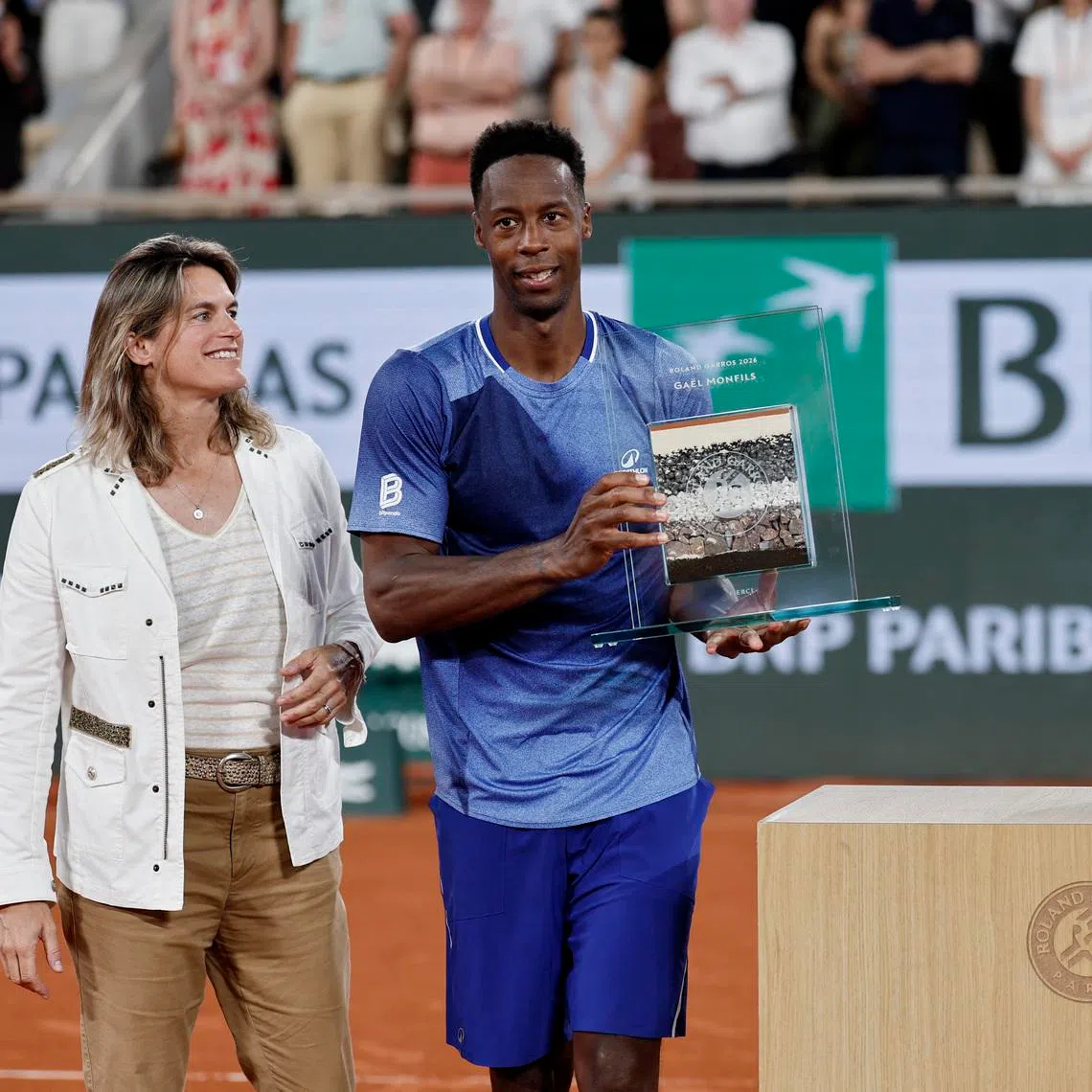 France's Gael Monfils poses with an award from Roland Garros after losing his first round match against France's Hugo Gaston.
